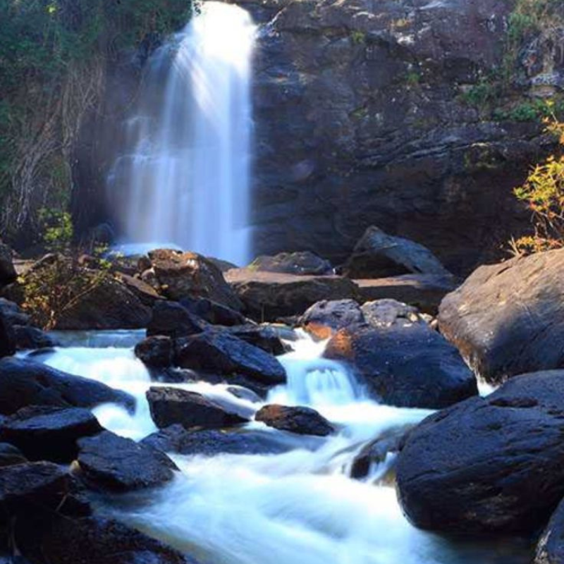A powerful three-layered waterfall descending into a pool at Soochipara.