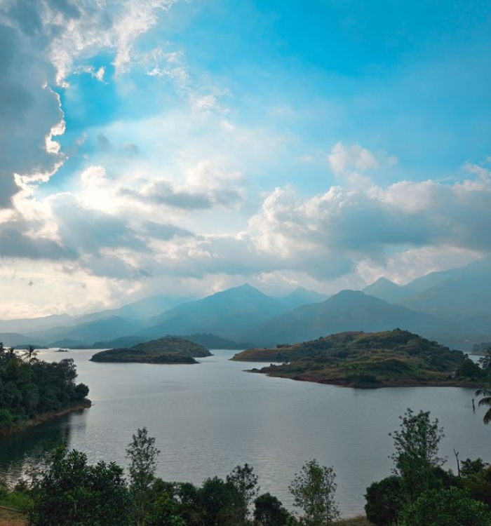 Speedboats on the reservoir at Banasura Sagar Dam with hills in background.