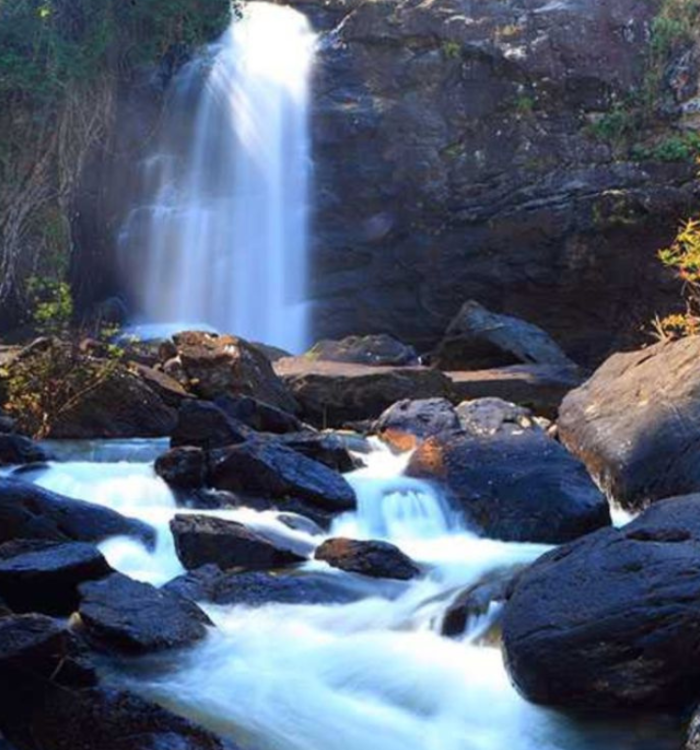 A powerful three-layered waterfall descending into a pool at Soochipara.
